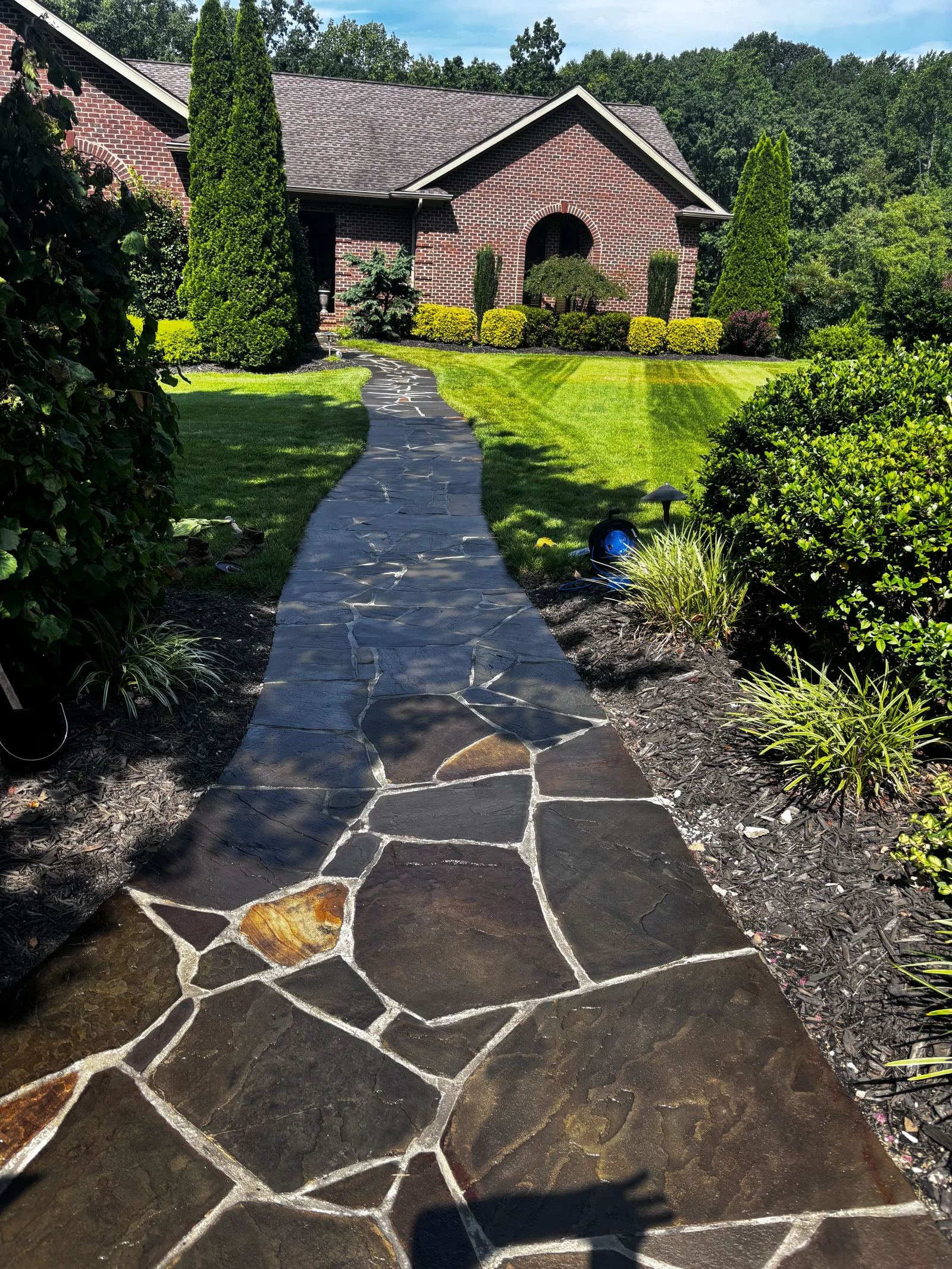 Irregular flagstone walkway with white mortar joints leading to brick home entrance