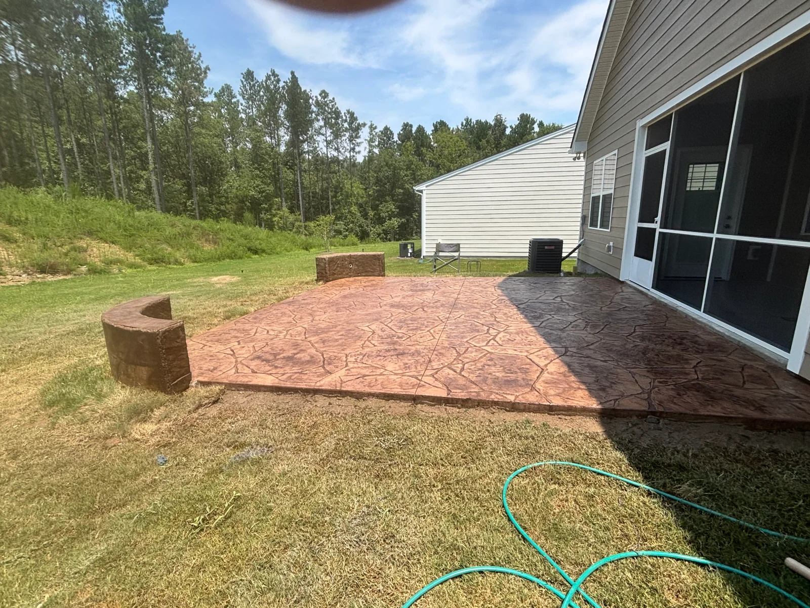 Stamped concrete patio with stone pattern, built-in benches, and fire pit area