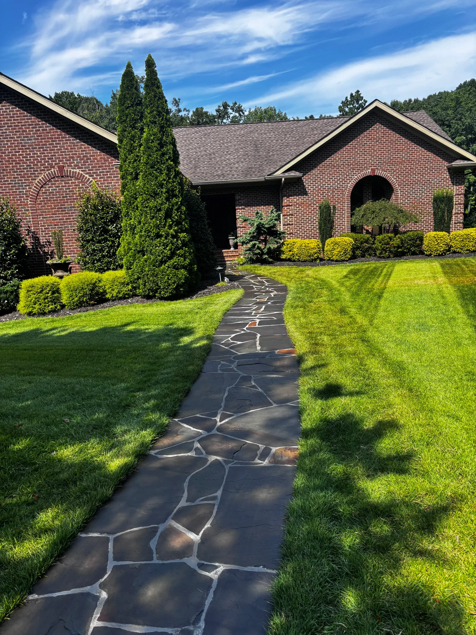 Flagstone walkway with white mortar joints flanked by green lawn and landscaping