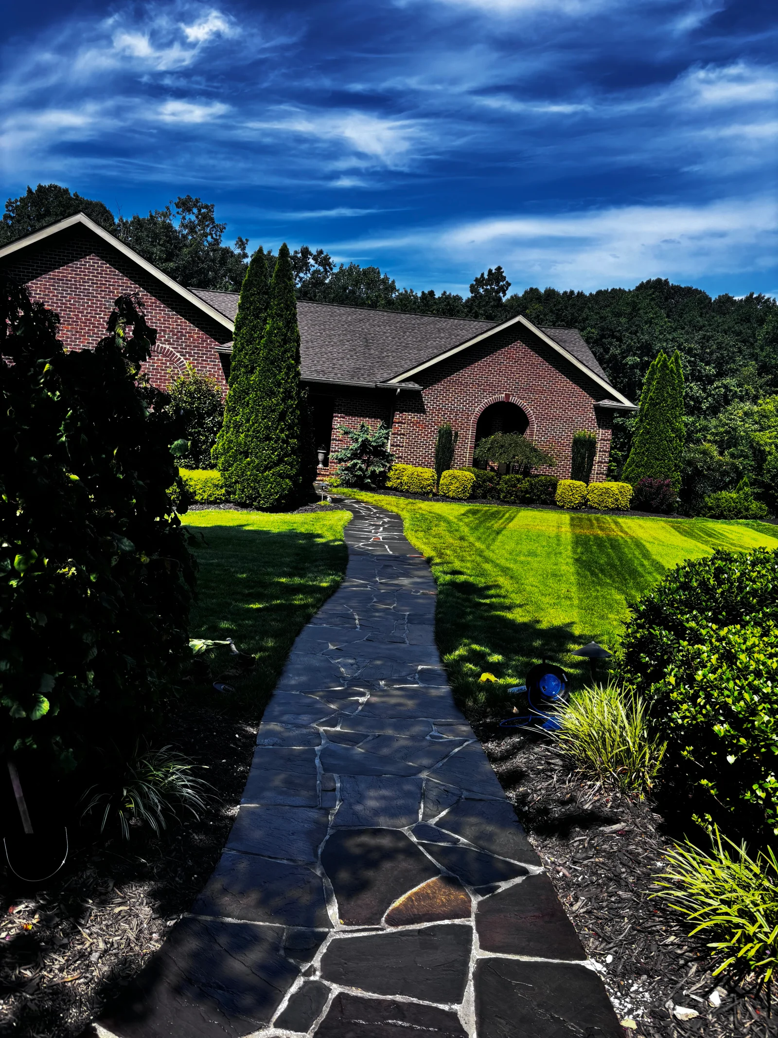 Dark slate flagstone walkway with white mortar joints bordered by landscaping beds