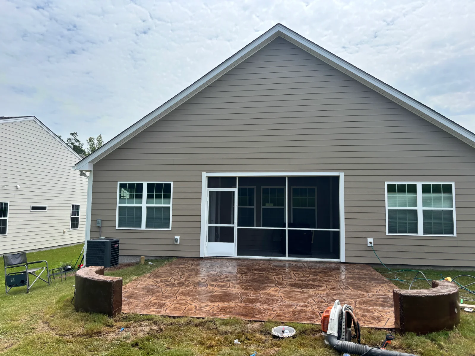Stamped concrete patio with wood-grain pattern in front of gray residential home