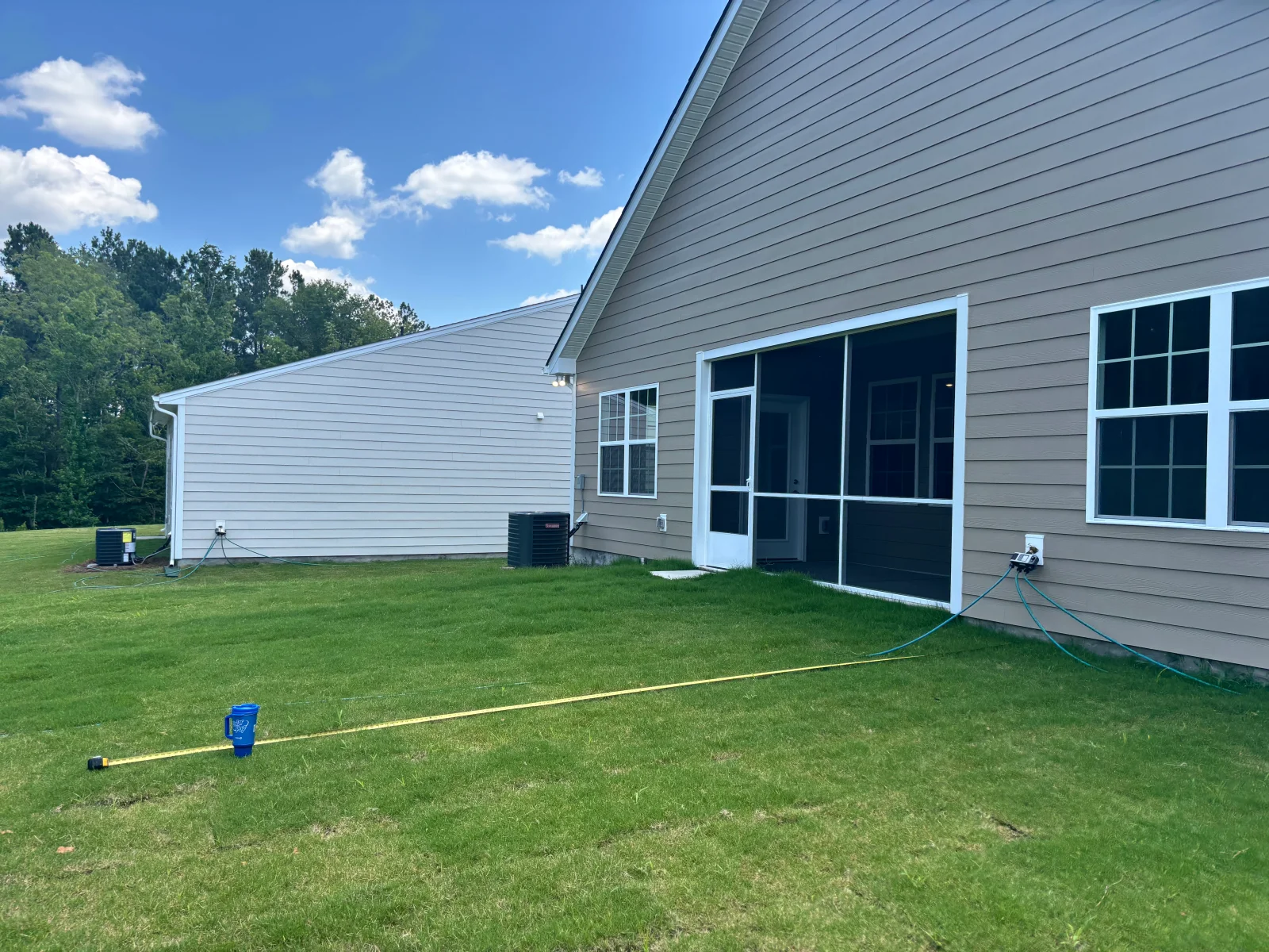 Concrete foundation with white vinyl siding, large windows, and utility lines on residential property