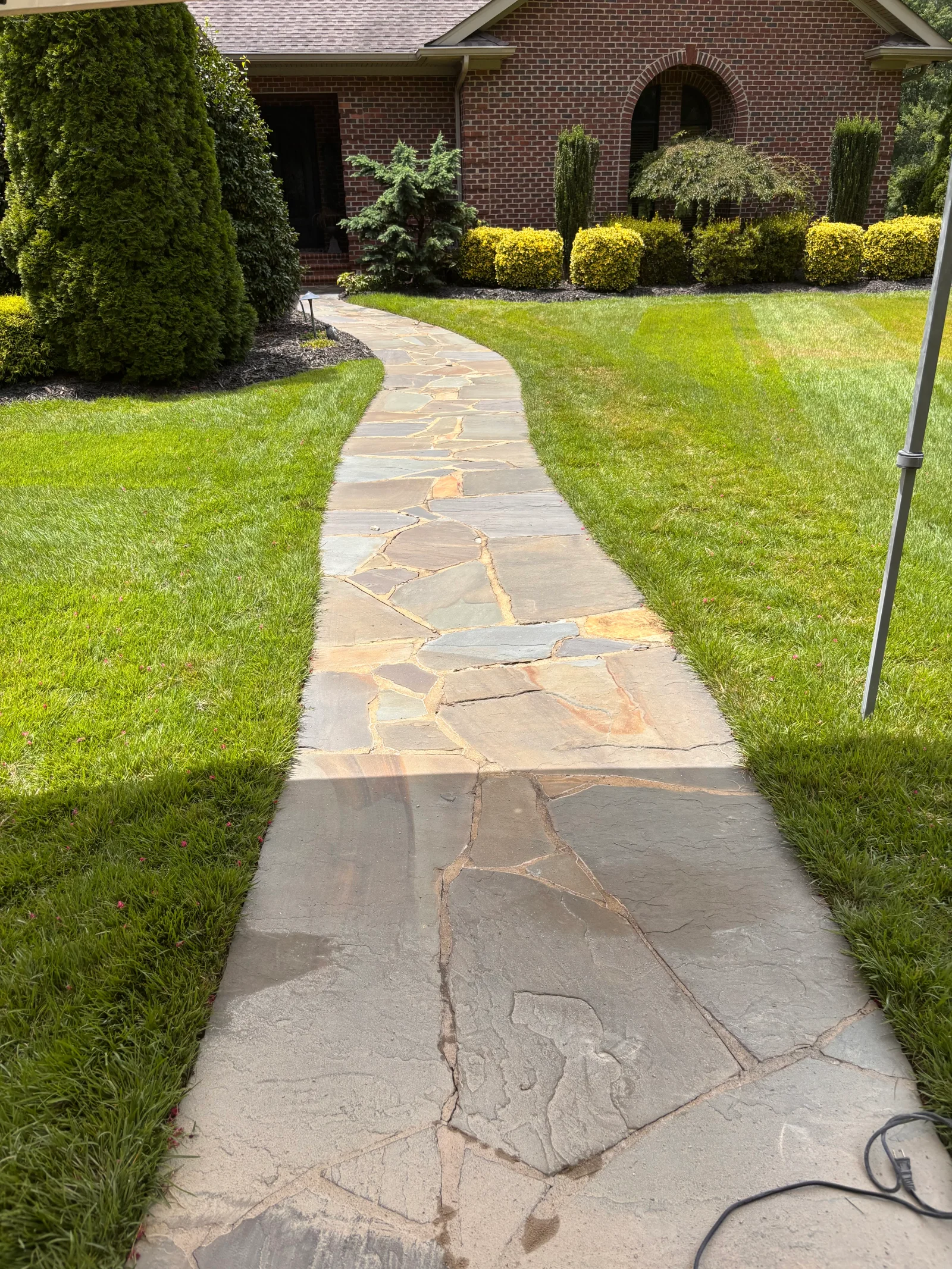 Curved flagstone walkway with natural stone edges, bordered by lawn and landscape beds