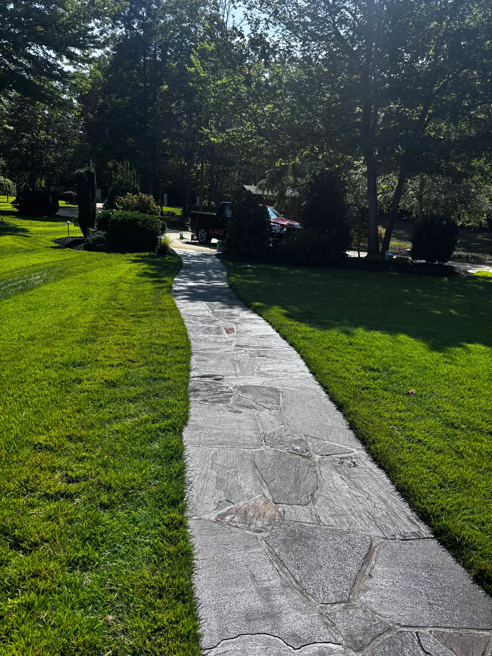 Flagstone walkway with natural stone pavers flanked by manicured lawn and mature trees