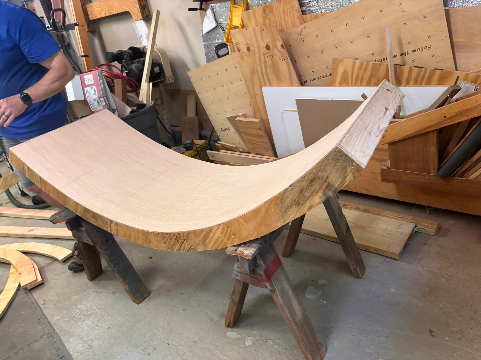 Light wood countertop with curved edge and live wood edge detail during fabrication on wooden support base