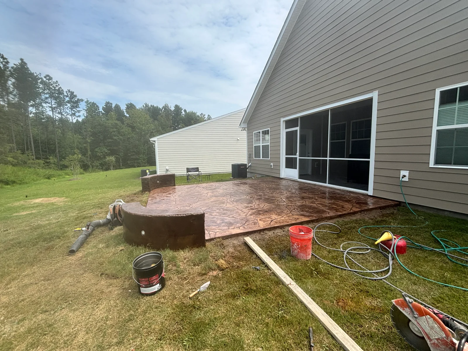 Stamped concrete patio with decorative pattern and earth-tone finish next to residential home