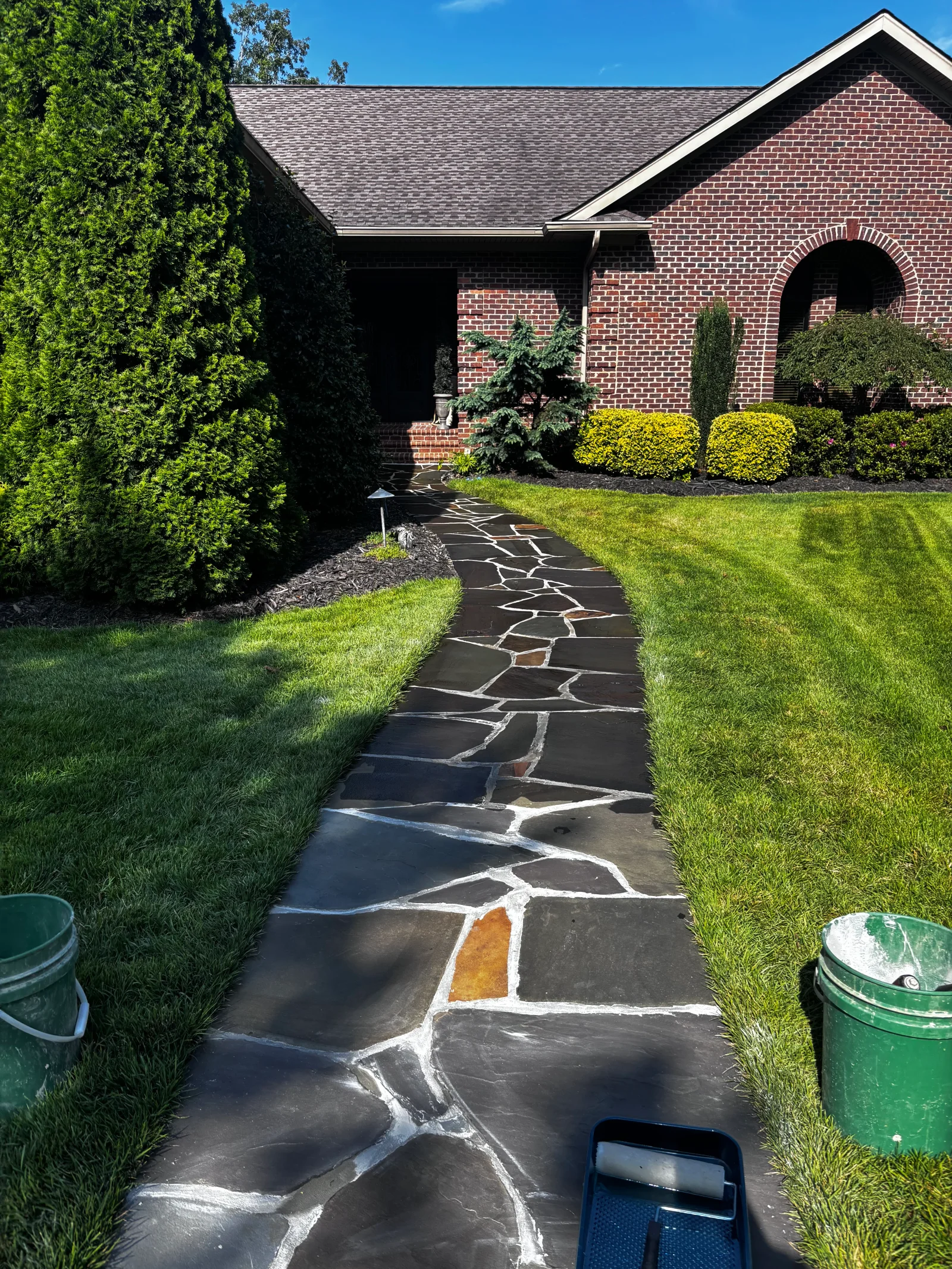 Black flagstone walkway with white mortar joints and colored accents between lawn areas